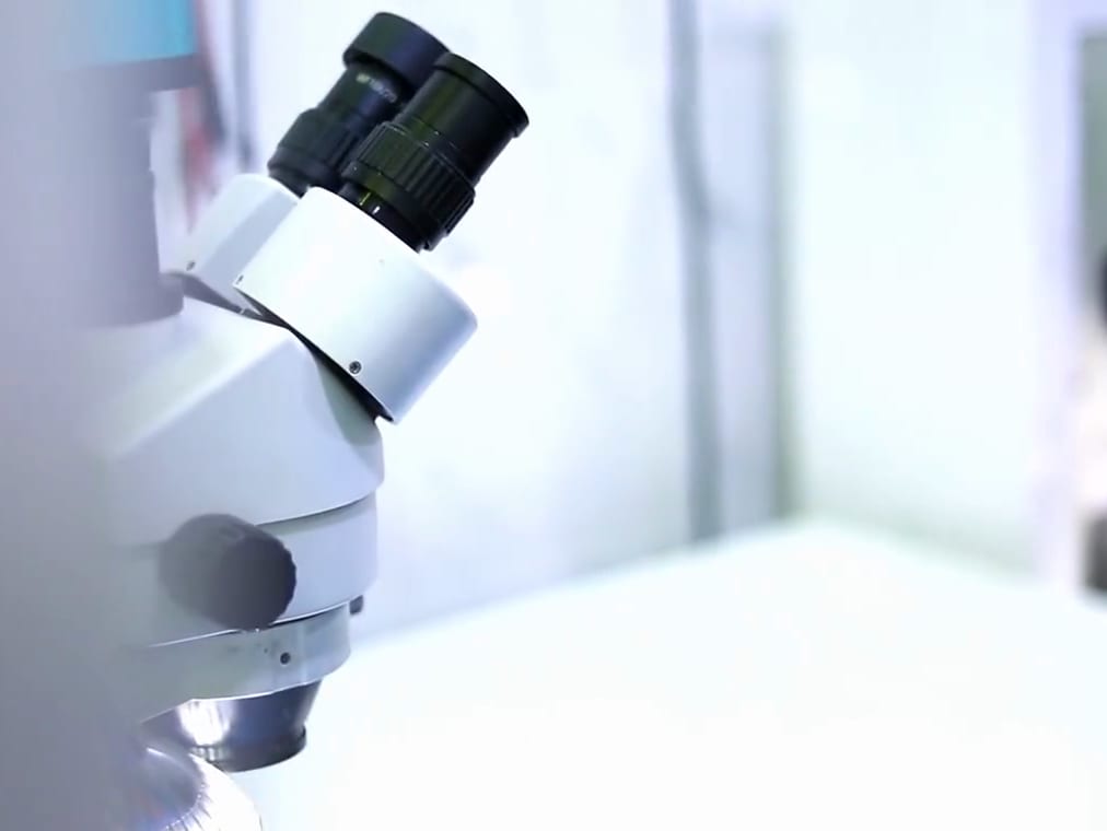 A laboratory microscope in a bright, white lab.