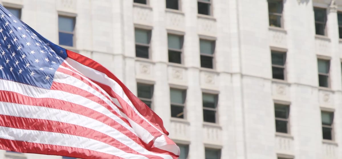 A United States flag in front of a government building.